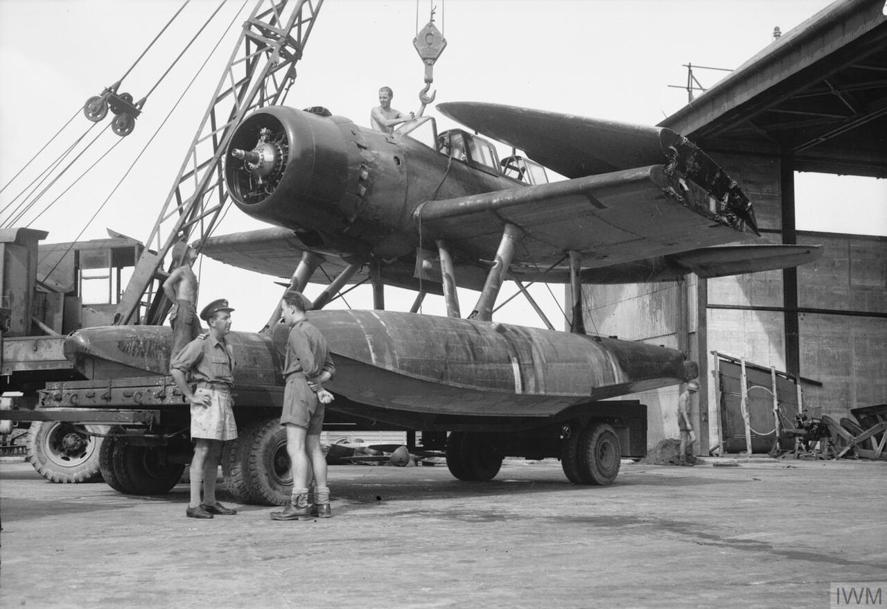 A Japanese Aichi E13A reconnaissance seaplane (codenamed 'Jake' by the Allies) is loaded aboard a flatbed truck at Seletar airfield by members of 126 Repair and Salvage Unit (RAF).
