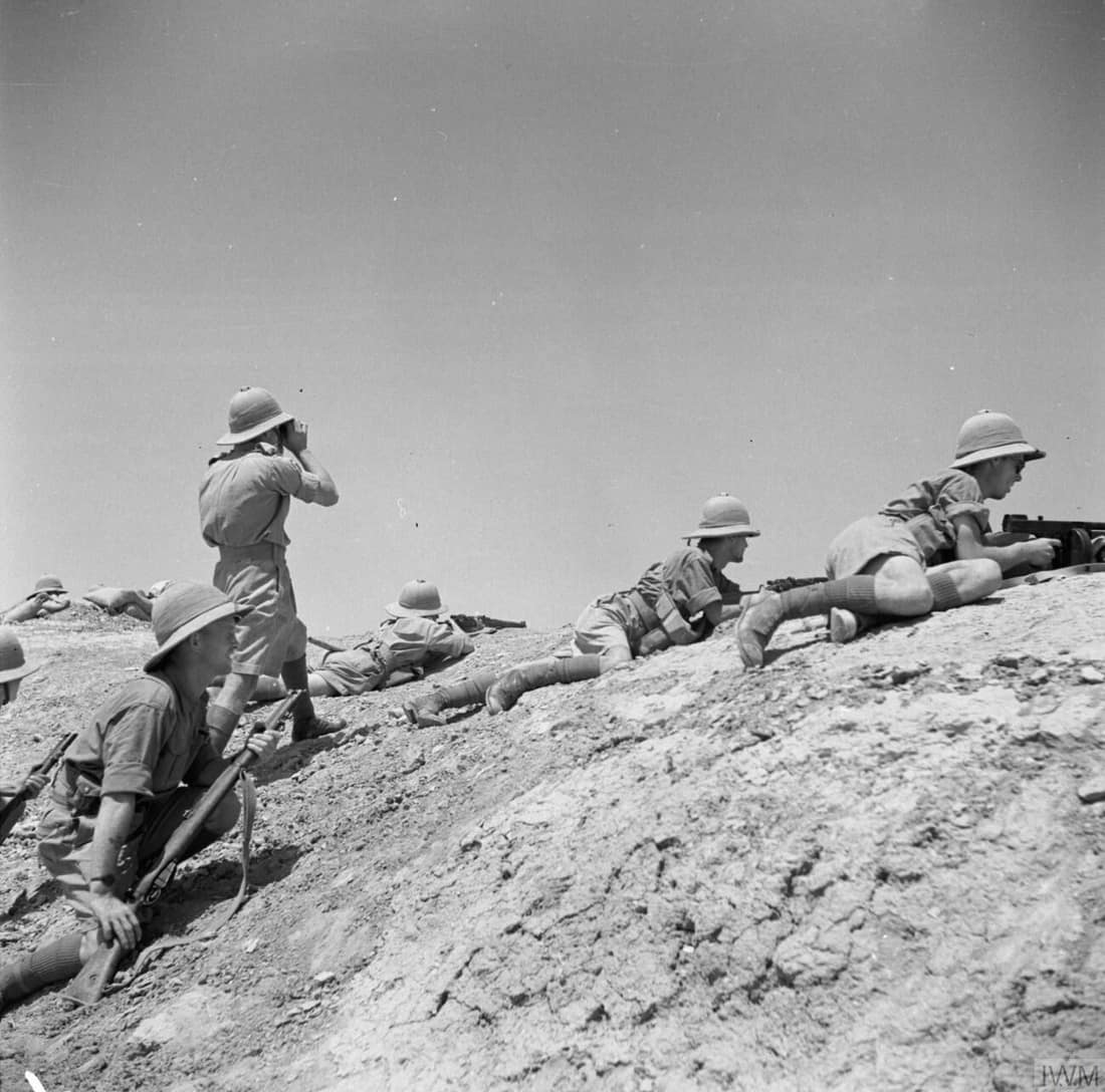 A firing party provide cover for a party of Royal Engineers who were building a temporary bridge near Ramadi, a stronghold of the Iraqi Rebels, 1 June 1941.
