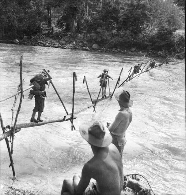 New Guinea. On the road to Buna Australian troops cross a stream on an improvised bridge.