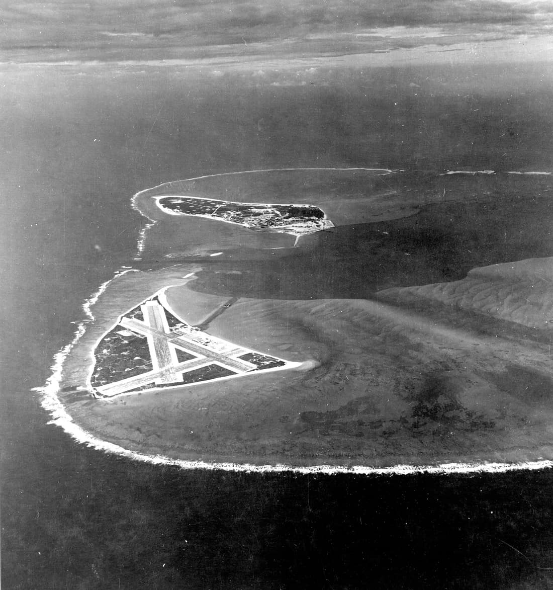 Aerial photograph of Midway Atoll, looking just south of west across the southern side of the atoll, 24 November 1941. Eastern Island, then the site of Midway's airfield, is in the foreground. Sand Island, location of mo