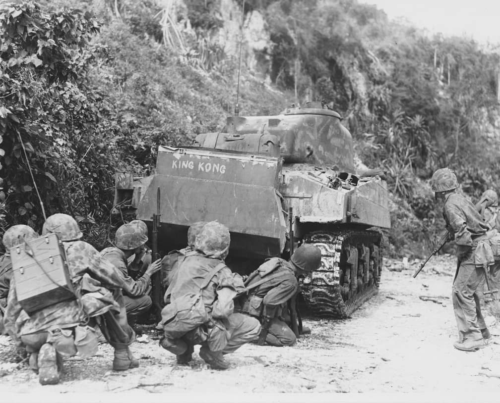 Marines take cover behind one of their medium tanks while cleaning out the northern north end of the island of Saipan. The Japanese were well dug in and making their last stand. July 8, 1944.