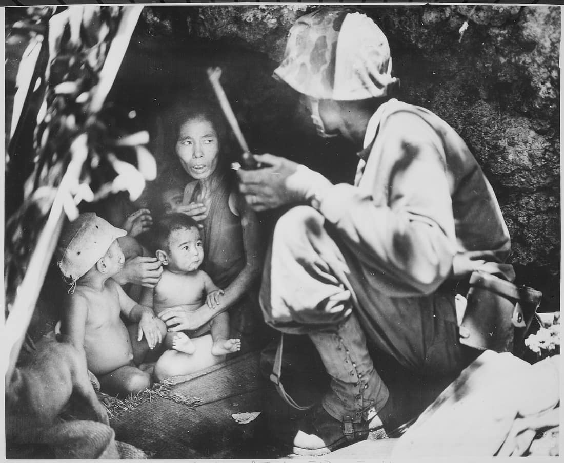 The marine is First Lieutenant Robert B. Sheeks, a combat intelligence and Japanese language officer with the 2nd Marine Division. He is talking the woman and her children into leaving the cave and going to the internmen