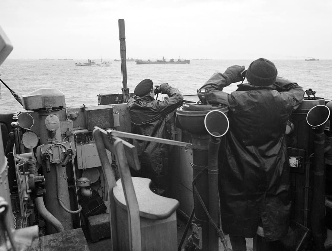 Officers on the bridge of a destroyer, escorting a large convoy of ships keep a sharp look out for attacking enemy submarines during the Battle of the Atlantic. October 1941