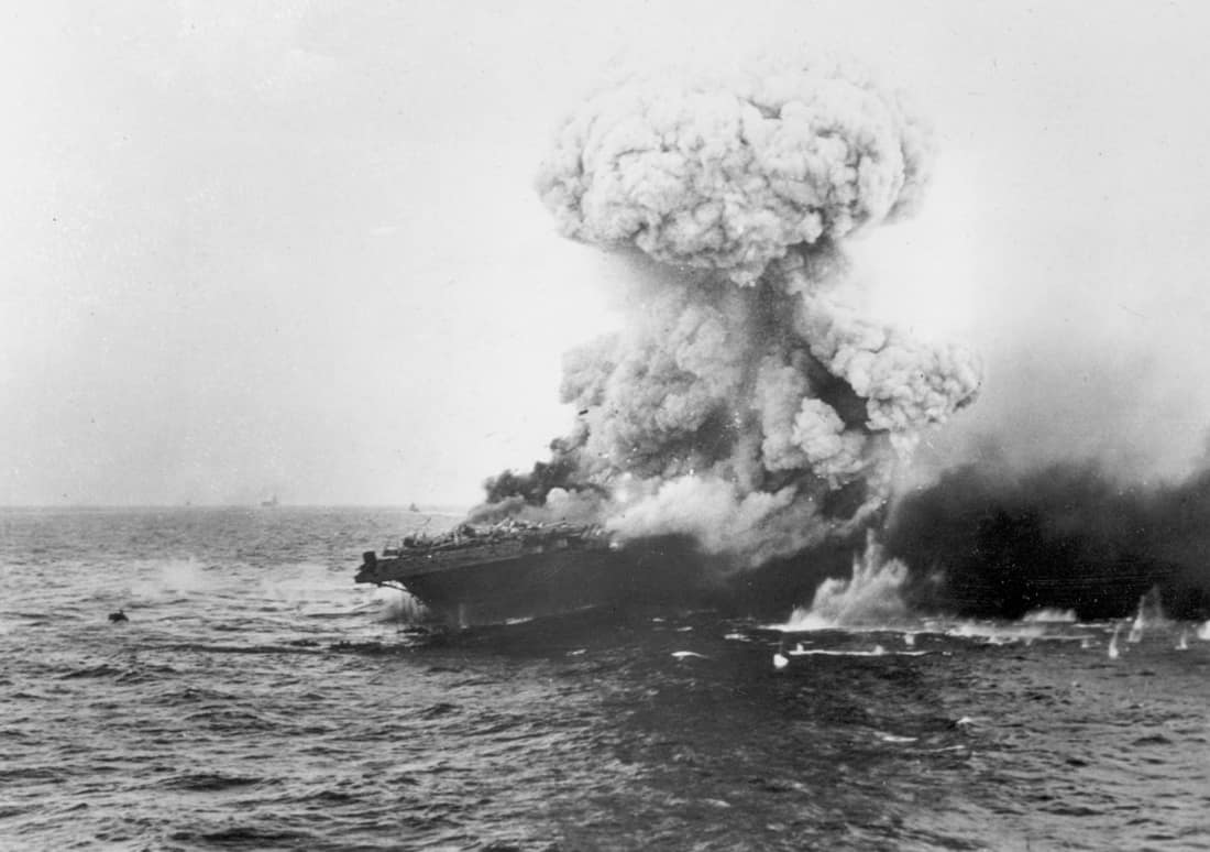 A mushroom cloud rises after a heavy explosion on board the U.S. Navy aircraft carrier USS Lexington (CV-2), 8 May 1942. This is probably the great explosion from the detonation of torpedo warheads stowed in the starboar