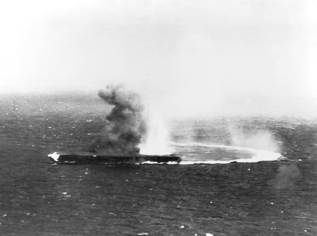 Japanese aircraft carrier Shōkaku under dive bombing attacks by USS Yorktown (CV-5) planes, during the morning of 8 May 1942. Flames are visible from a bomb hit on her forecastle.