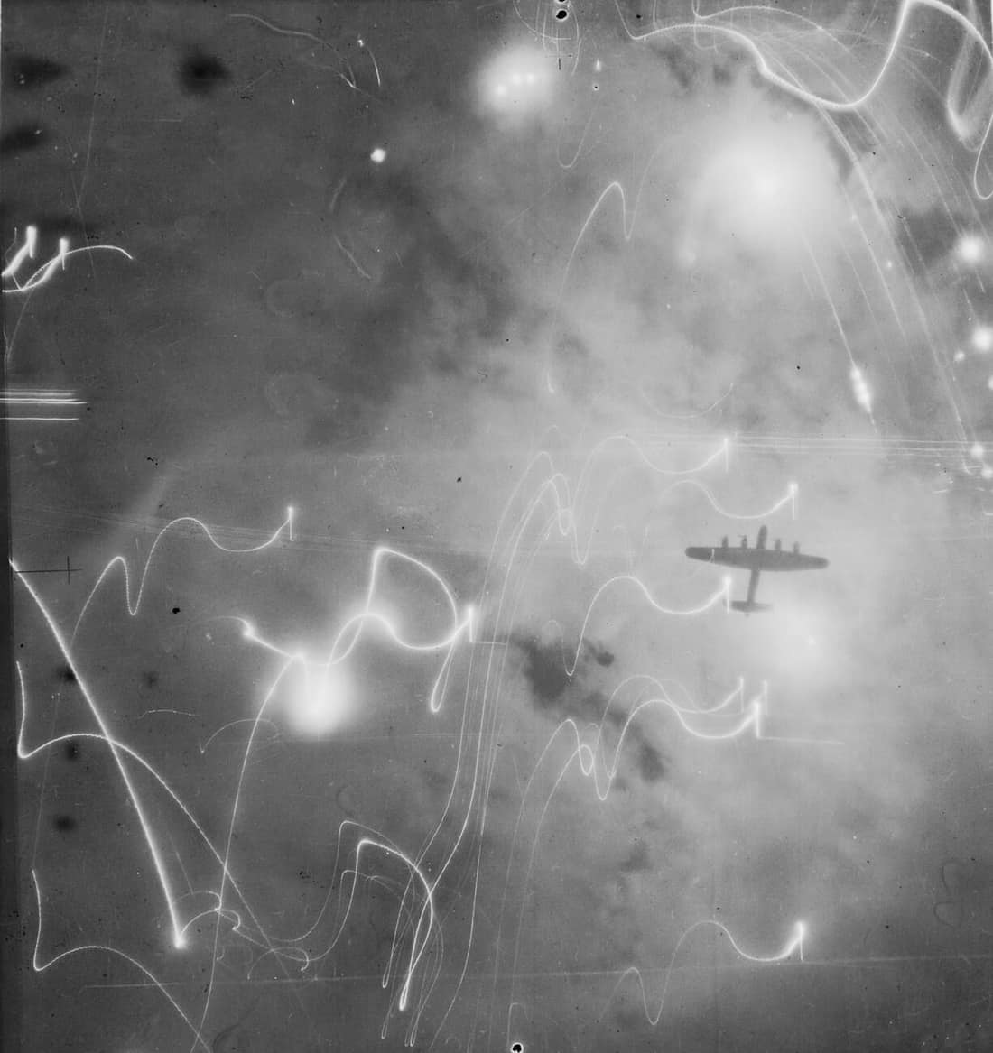 An Avro Lancaster of No. 1 Group, Bomber Command, silhouetted against flares, smoke and explosions during the attack on Hamburg, Germany, by aircraft of Nos. 1, 5 and 8 Groups on the night of 30/31 January 1943. This rai