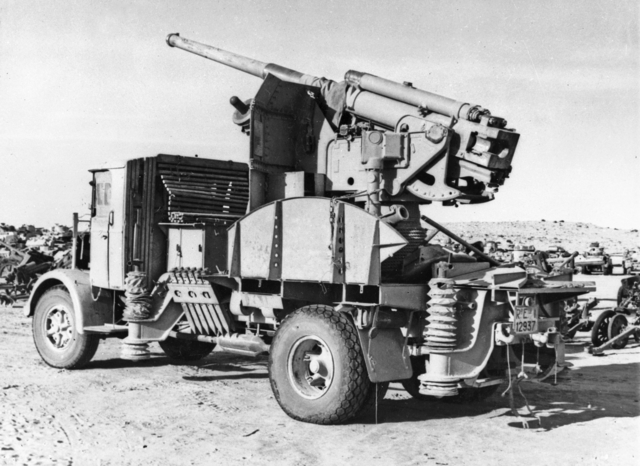 AWM photo caption: 1943-02-09. EIGHTH ARMY'S ADVANCE. AN ITALIAN 90/53 90MM GUN ON A TRUCK MOUNTING JOINING THE ROWS OF DERELICT AXIS VEHICLES AND EQUIPMENT JETTISONED BY ROMMEL'S ARMY.