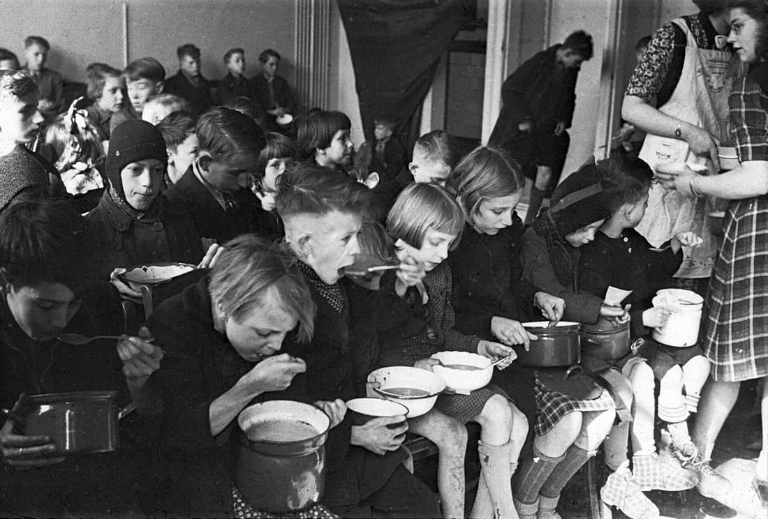 Foto uit de collectie Huizinga van het NIOD. Kinderen eten een halve liter bijvoeding per dag tijdens de Hongerwinter, verschaft door het Interkerkelijk Bureau. Menno Huizinga was onderdeel van de Ondergedoken Camera en 