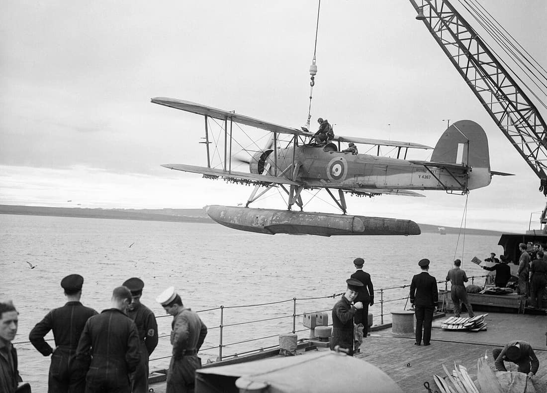 A Fairey Swordfish being hoisted aboard HMS MALAYA, October 1941. After a reconnaissance flight, a Fairey Swordfish sea plane returns to HMS MALAYA and is hoisted in board.