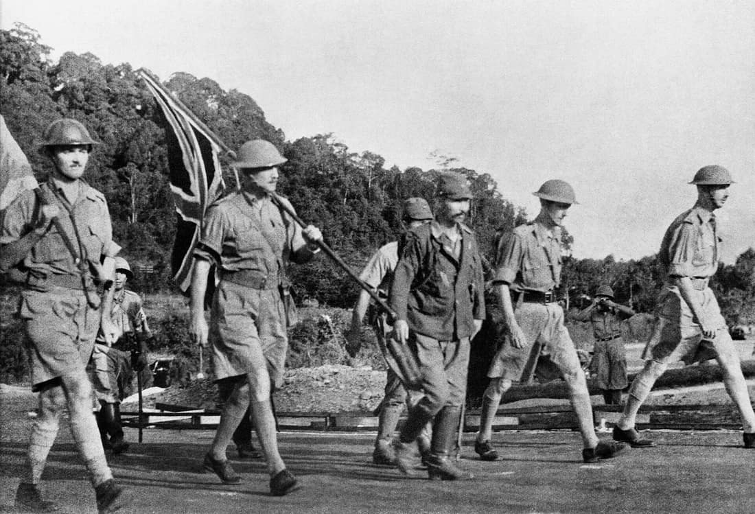 Lieutenant-General Percival and his party carry the Union flag on their way to surrender Singapore to the Japanese. Left to Right: Major Cyril Wild (carrying white flag) interpreter; Brigadier T. K. Newbigging (carrying 