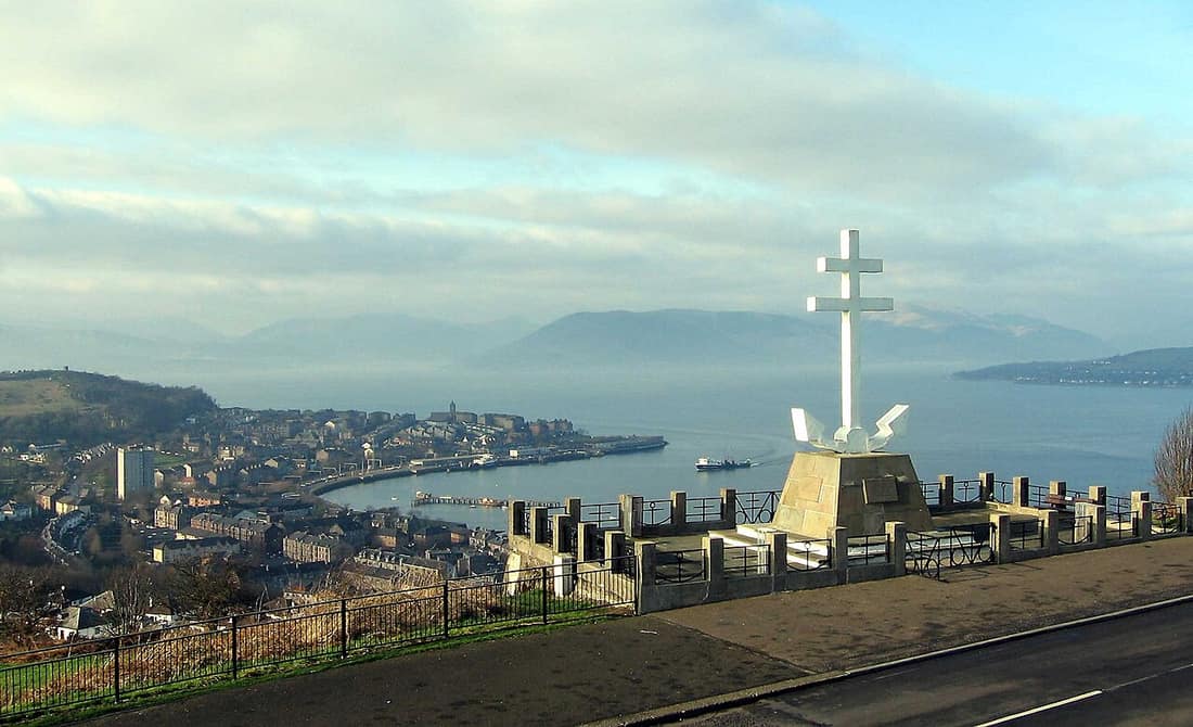 The Free French Memorial on Lyle Hill, Greenock, has views over Gourock and the Firth of Clyde. The Caledonian MacBrayne ferry MV Juno approaches the pier, and MV Saturn is at the pier. The Argyll hills are shrouded in m