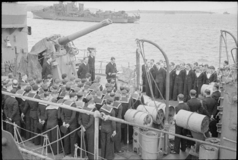 Church service aboard British destroyer HMS Javelin. A 4-inch QF Mk V anti-aircraft gun is seen the left background. Depth-charges and launcher are seen in the right foreground