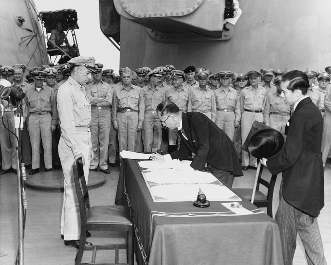 Japanese Foreign Minister Mamoru Shigemitsu signs the Instrument of Surrender on behalf of the Japanese Government, on board USS Missouri (BB-63), 2 September 1945. Lieutenant General Richard K. Sutherland, U.S. Army, wa