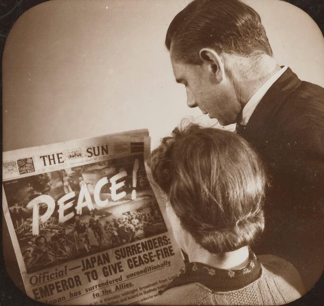 Mavis and Harry Beanham looking at the headlines on The Sun newspaper at Balls Head, Waverton, 15 August 1945. Japan accepted the terms of the Potsdam Declaration, announcing its unconditional surrender to the Allies. Th