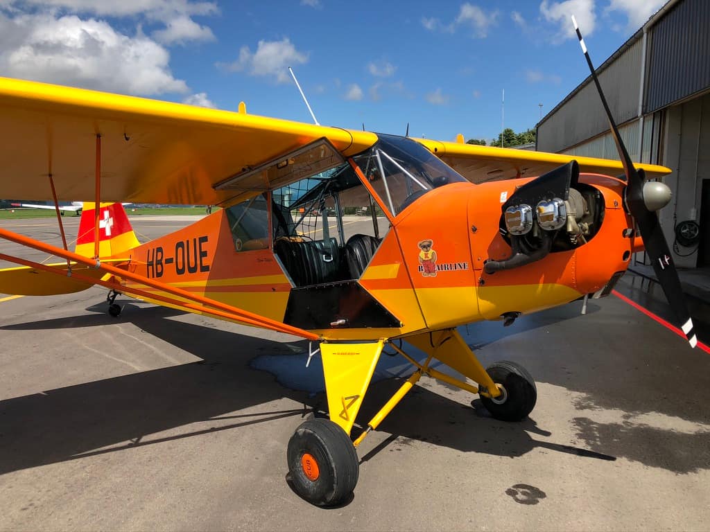 Piper J-3C-65 HB-OUE with rare Rolls Royce O-200A 100hp engine. s/n 12315. Flugplatz Fricktal Schupfart aerodrome LSZI, Switzerland. Engine is handpropped.