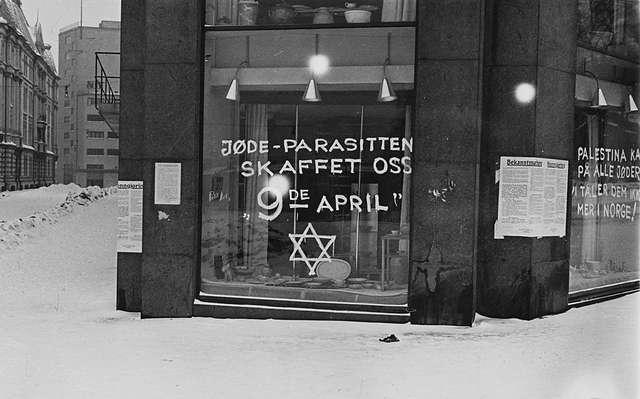 Anti-Semite graffiti and German posters on a shop in Oslo, occupied Norway during the Second World War. The graffiti proclaims (left to right): Jøde-parasitten skaffet oss 9de april (The Jew parasite got us 9 April) and 