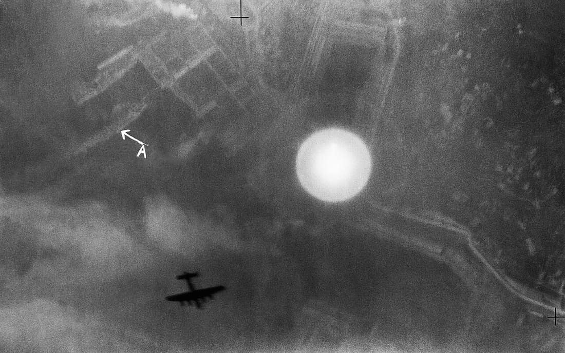 An Avro Lancaster silhouetted over the Italian port of La Spezia on the night of 13/14 April 1943. Annotated section of a vertical aerial photograph taken during a night raid on the docks at La Spezia, Italy. An Avro Lan