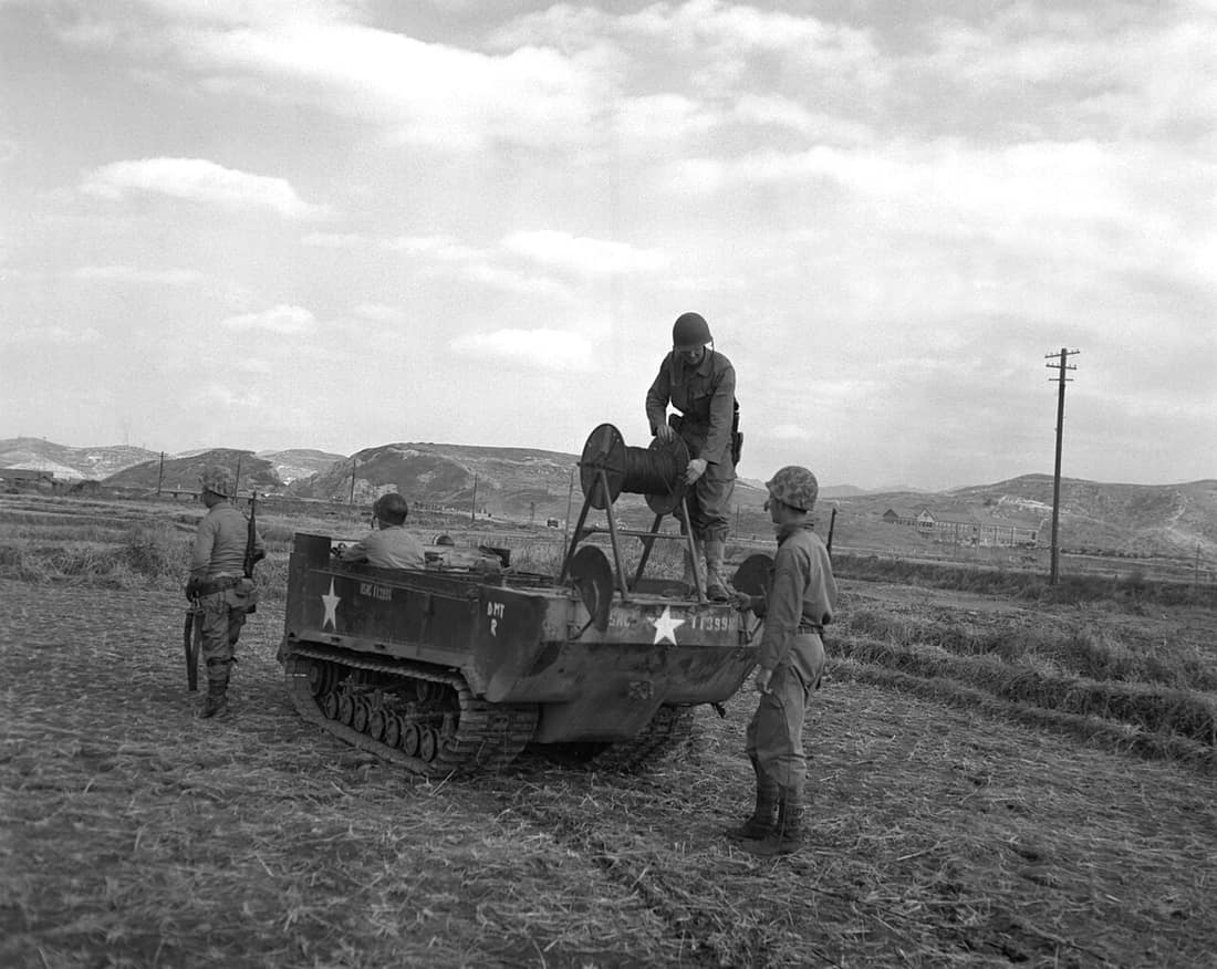 Weasel of First Marine Division communication section laying telephone wire across rice paddies in Hungnam area.