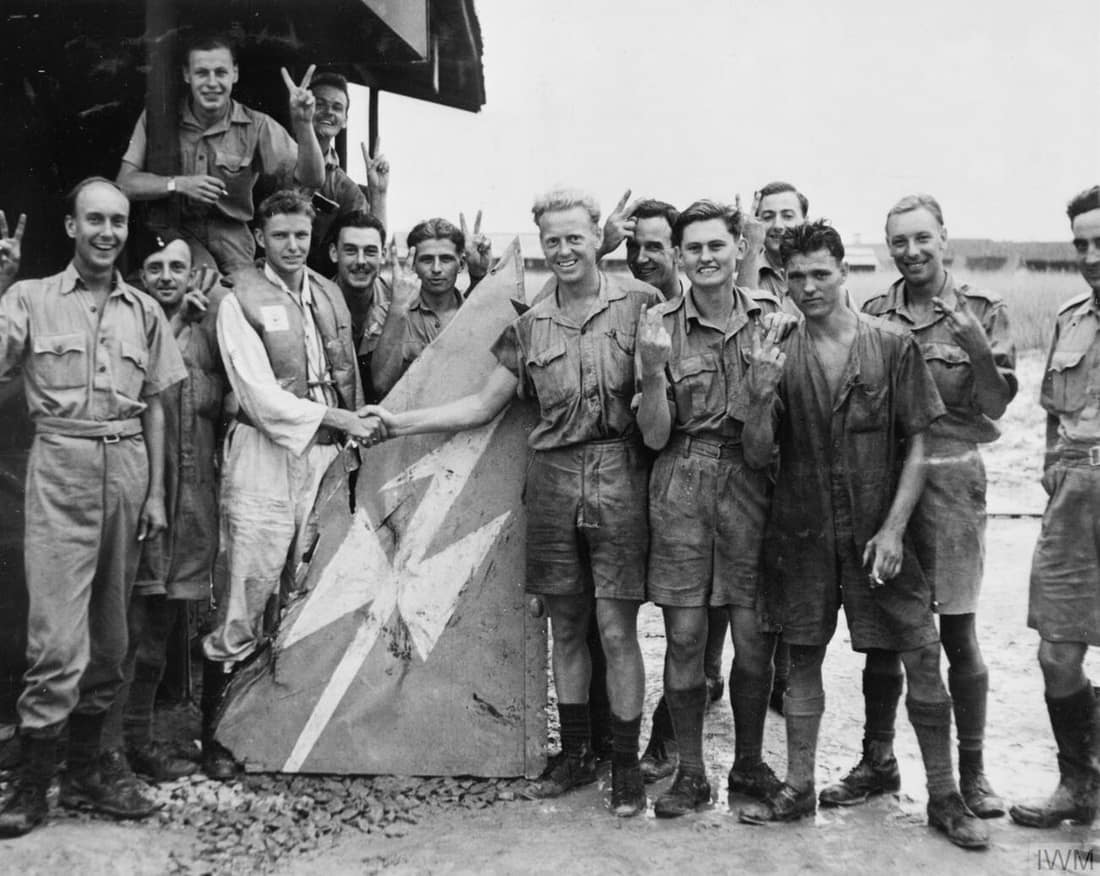 Buffalo pilots of No. 488 (New Zealand) Squadron based at Kallang display the tail fin of a Japanese aircraft which they shot down over Johore, Malaya, January 1942.