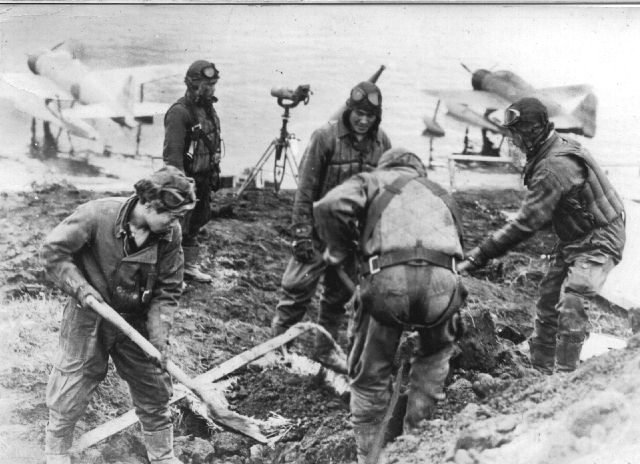 Japanese fighter pilots. At the plane anchorage in the background can bee seen two Nakajima A6M2-N Type 2 Fighter Model 11 sea-planes. These float plane versions of the "Zero" fighter had the allied reporting name "Rufe"