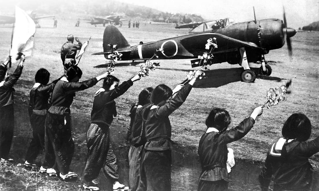Chiran high school girls are waving farewell with cherry blossom branches to a taking-off kamikaze pilot. The pilot is Second Lieutenant Toshio Anazawa of Army Special Attack Unit (20th Shinbu party). The aircraft, an Ar