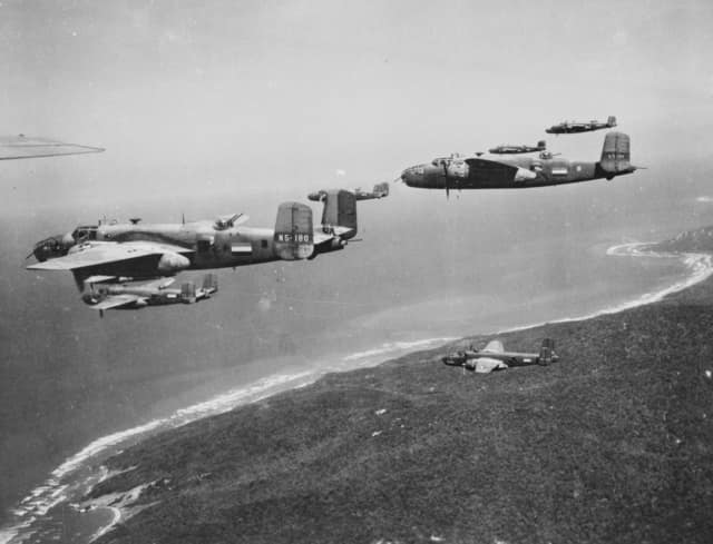 AWM Caption: Darwin. c. 1943. Eight North American B25 Mitchell bomber aircraft fly over the coast near Darwin. Note the aircraft are all carrying Netherlands East Indies (NEI) registrations and markings.