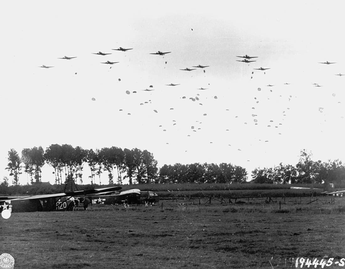 US Army paratroopers are dropped near Grave, Netherlands while livestock graze near gliders that landed earlier. This was the beginning of Operation Market Garden during World War II, which resulted in heavy Allied losse