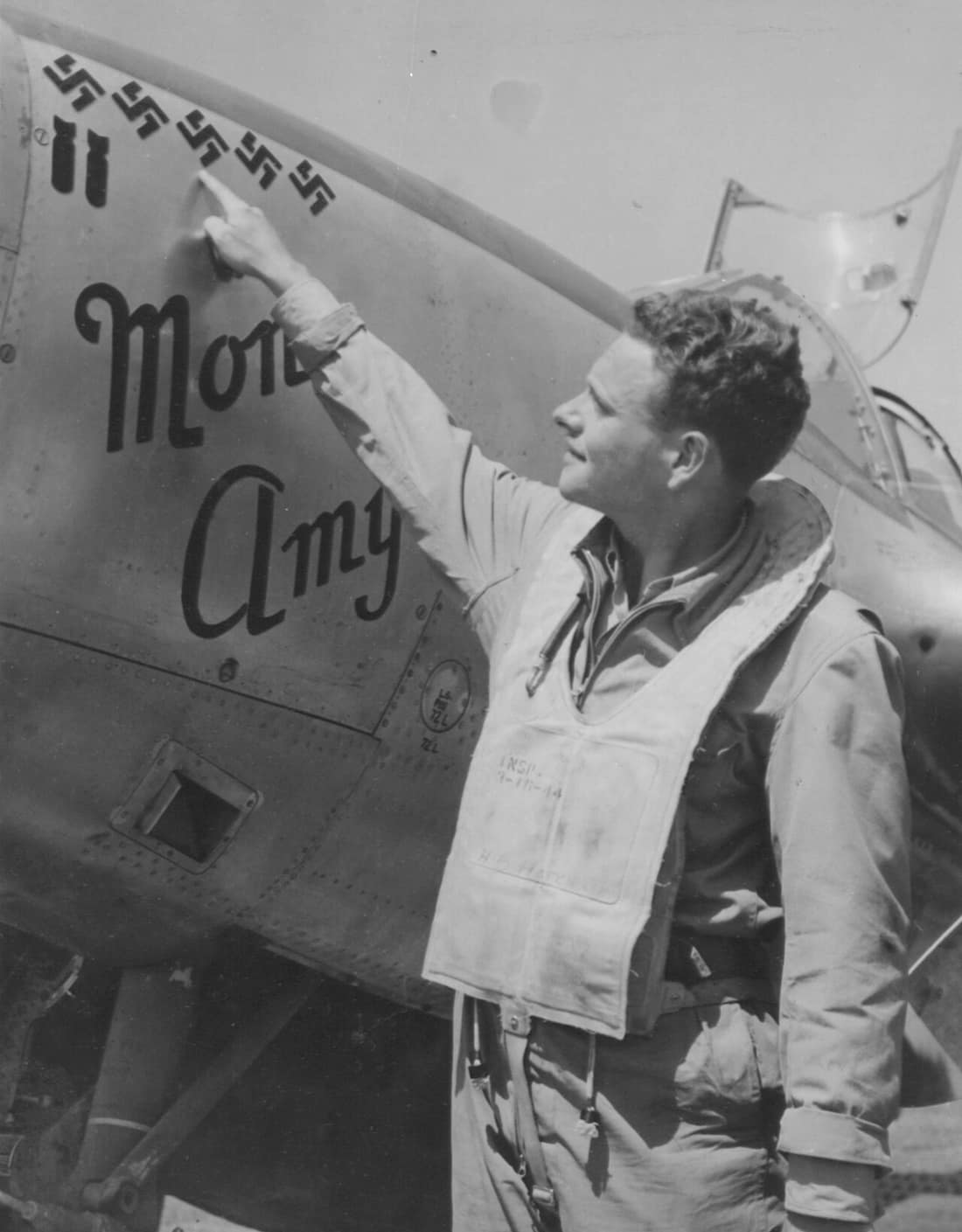 2Nd Lt. Herbert B. Hatch Of Stockton, Calif. A Lockheed P-38 Lightning fighter pilot of the Mediterranean Allied AFs in Italy, proudly points to the 5 swastikas on the nose of his plane, that proclaim his victory over 5 