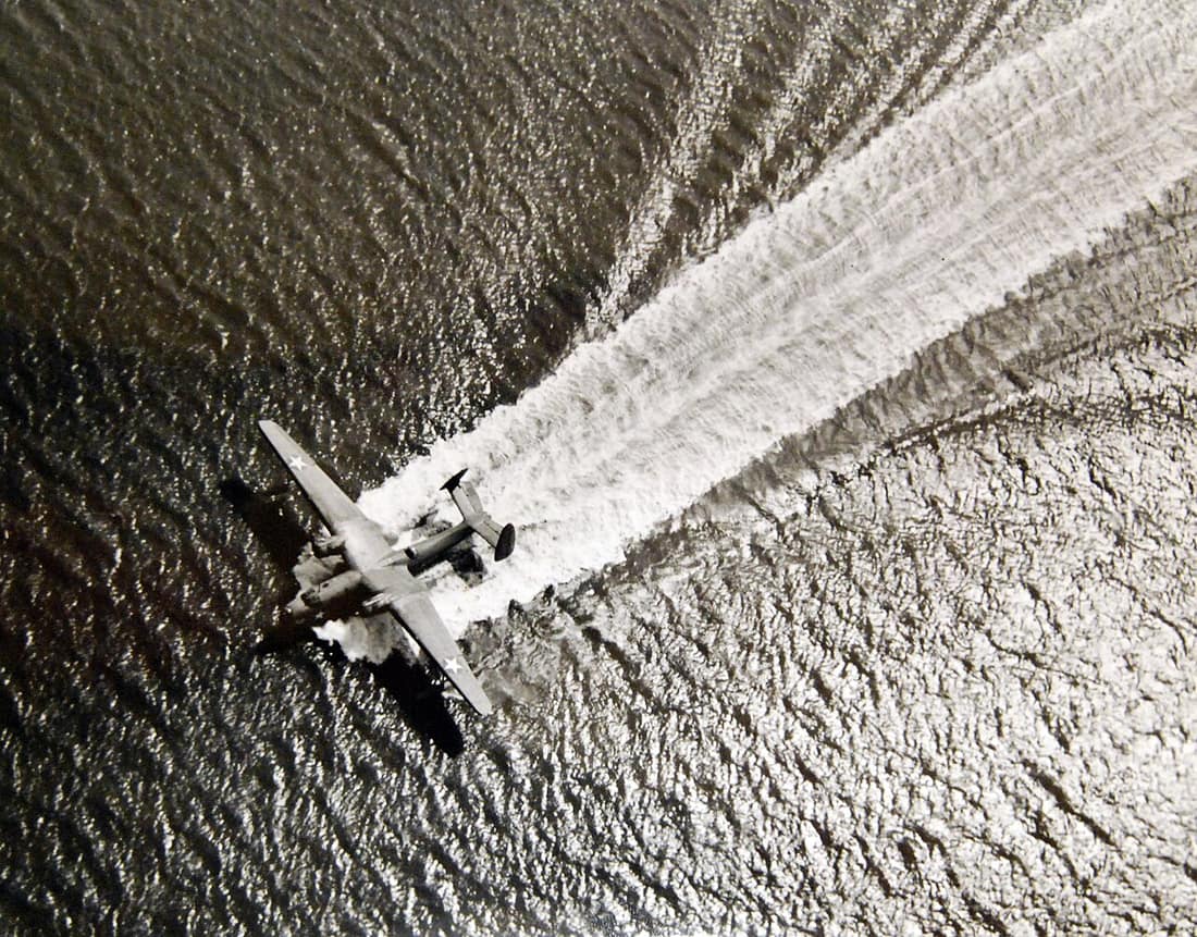 Lot-799-15: WWII-Aircraft. A Martin “Mariner” leaves a white-ribbon wake as it lands on the harbor of an East Coast Naval Air Station. These twin-engine, gull-wing patrol bombers fly for the Navy on anti-submarine patrol