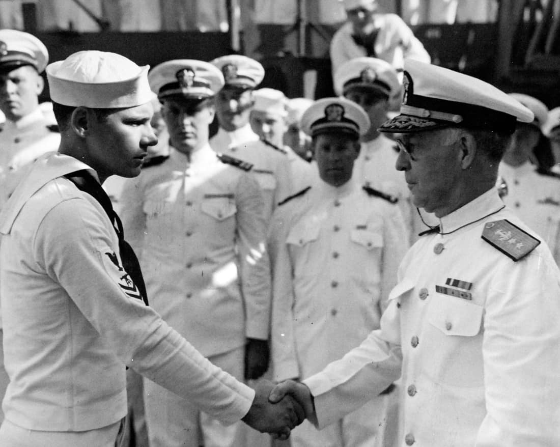 80-G-202067: USS Salt Lake City (CA-25), October 21, 1943. Rear Admiral Ernest G. Small, USN, former Commanding Officer, presenting Purple Heart medals to enlisted men wounded in the Pacific. Shown: FC 2/C Lewis E. LaCes