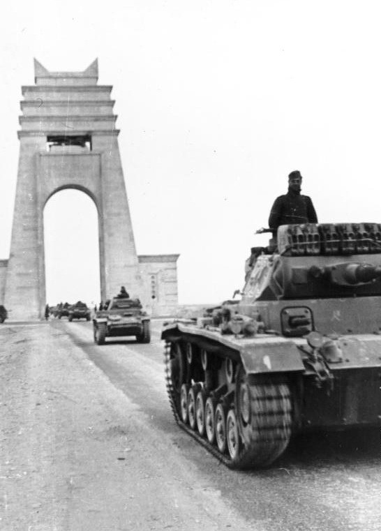 Panzer Mk IIIs and Mk IIs cross under the marble arch at Sirte as they reinforce the Italians in the western desert.