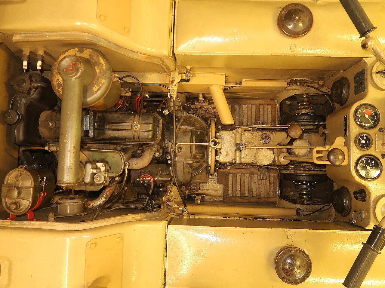 View from above into the hull of a 1942 NSU Kettenkrad on the drive train. Direction of travel to the right. The driver's seat and the covers above the steering brakes are removed. On the left of the picture is the engin