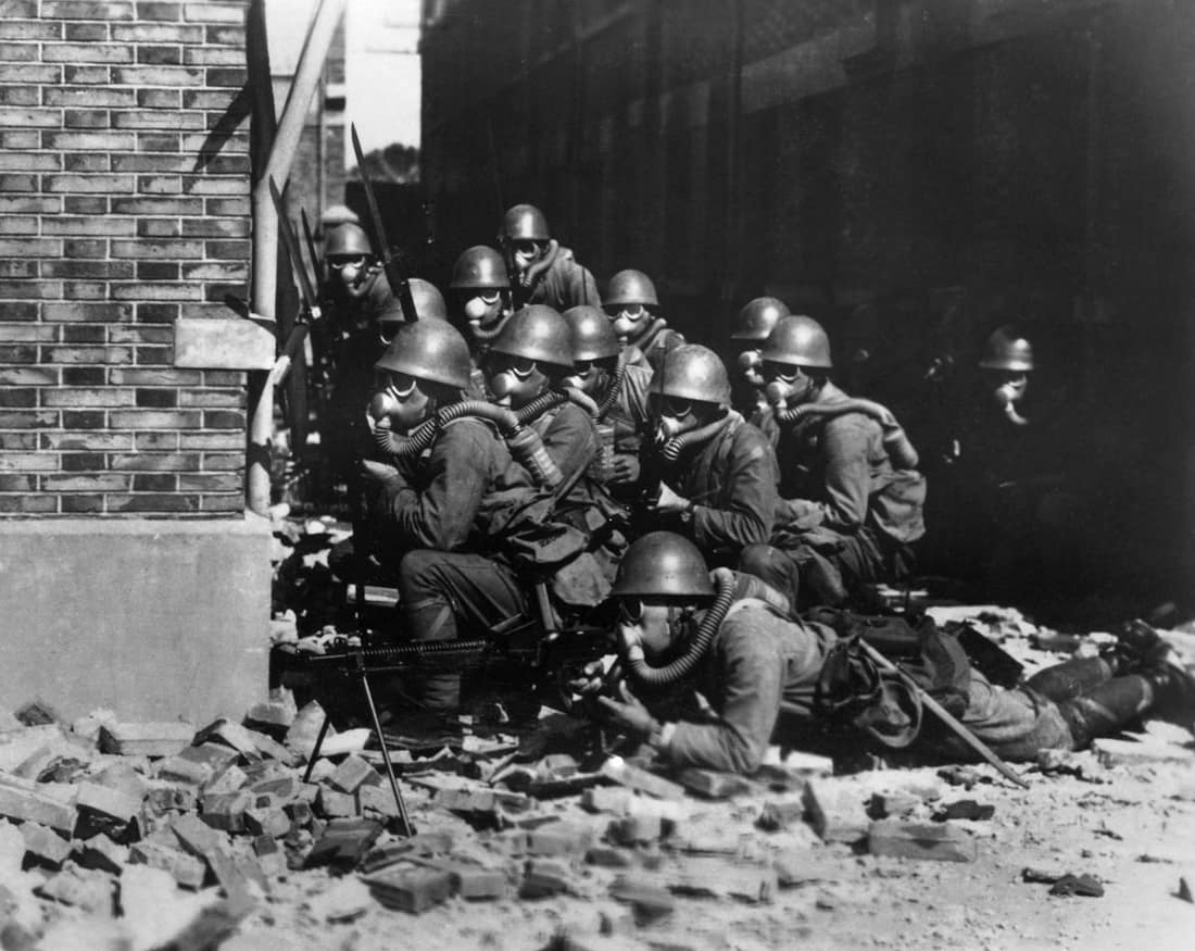 The Imperial Japanese Navy (IJN) Special Naval Landing Forces troops in gas masks prepare for an advance in the rubble of Shanghai, China.