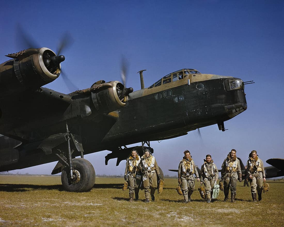 Short Stirling Mk I of No. 1651 Heavy Conversion Unit at Waterbeach in Cambridgeshire, 1942. Aircrew in full flying kit walking beneath the nose of Short Stirling Mark I, N3676 'S', of 1651 Heavy Conversion Unit at Water