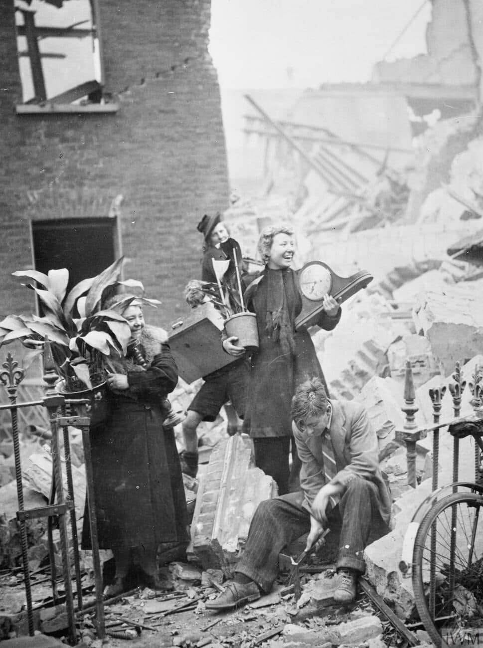 Air Raid Damage in London, 1940 Women salvaging prized possessions from their bombed house, including plants and a clock.