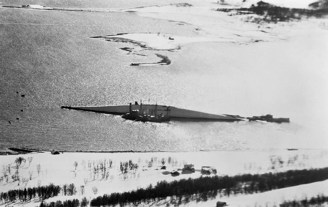 Low-level oblique photographic-reconnaissance aerial taken from De Havilland Mosquito PR Mark XVI (NS637) of No. 544 Squadron RAF, showing the capsized German battleship Tirpitz, lying in the Tromsø fjord near isle of Hå
